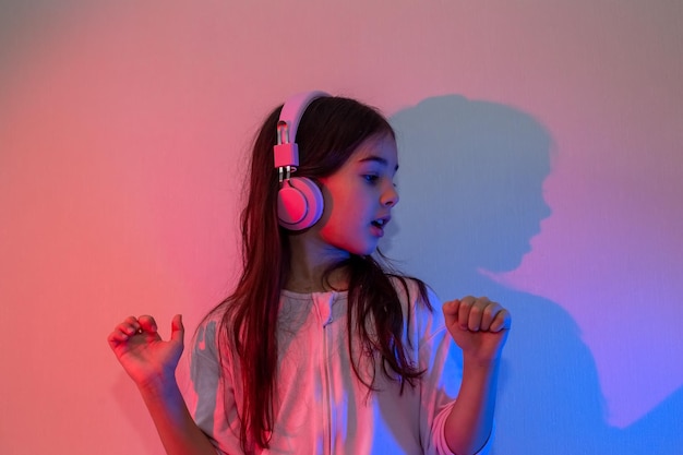 Retrato de una niña feliz bailando con auriculares rosas