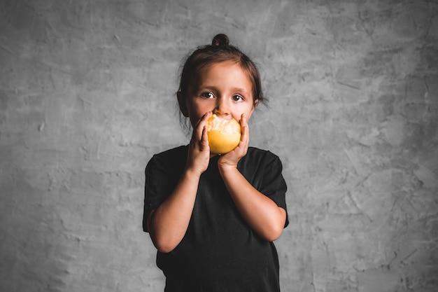 Retrato de una niña feliz comiendo una manzana