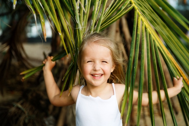 Retrato de la niña feliz con la hoja de palma.