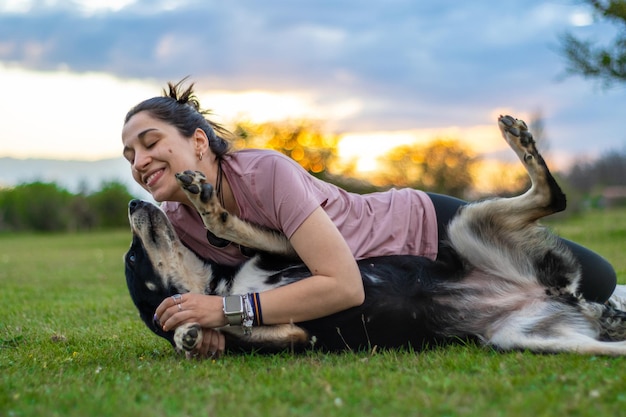 Retrato de una niña feliz jugando con su perro en el césped al atardecer