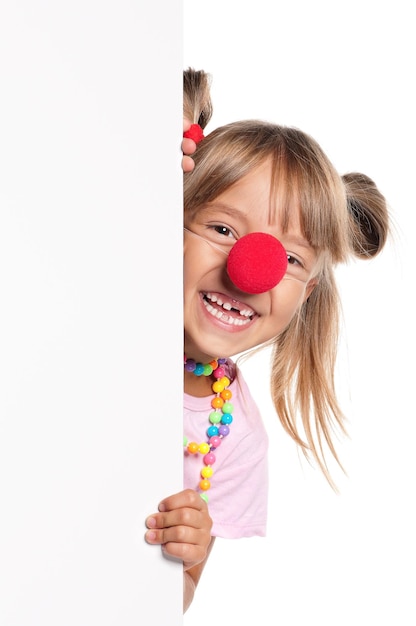 Retrato de una niña feliz con la nariz de payaso roja con blanco en blanco