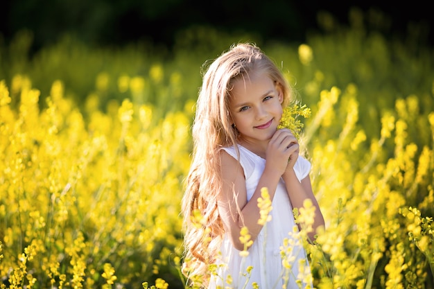 Retrato de una niña feliz en la naturaleza, en verano en un campo de violación.