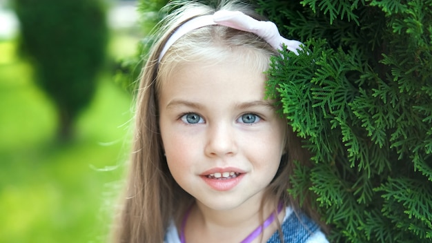 Retrato de niña feliz niño bonito de pie en el parque de verano