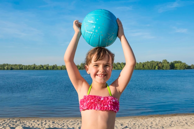 Retrato de una niña feliz con pelota en la playa Estilo de vida