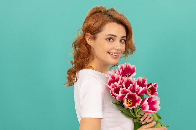 Retrato de niña feliz con ramo de flores de tulipán sobre fondo azul