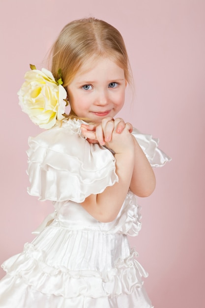 Retrato de una niña feliz con una rosa en el pelo en rosa