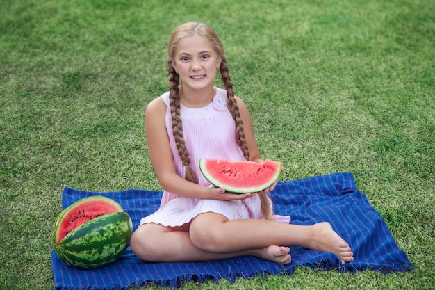 Retrato de niña feliz con sandía disfrutando de verano al aire libre durante el día.