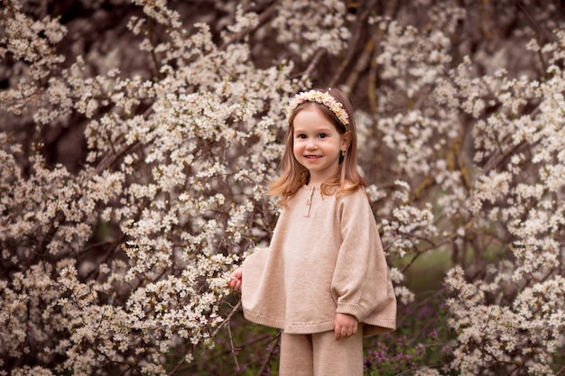 Retrato de una niña feliz sobre un fondo de árboles en flor.