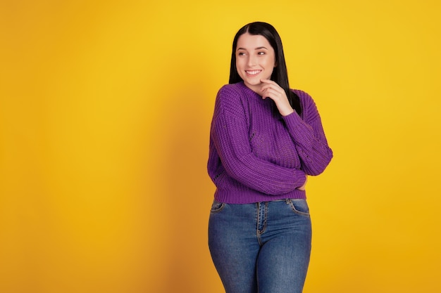 Retrato de niña feliz sueño alegre pensar mirar espacio vacío dedo toque barbilla aislado sobre fondo de color amarillo