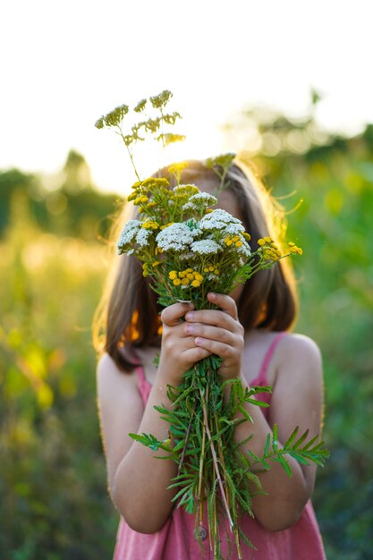 Retrato de una niña con flores en el campo.