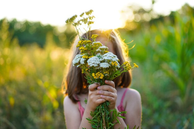 Retrato de una niña con flores en el campo.