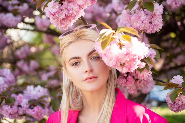 Retrato de niña en flores de hermosa joven en un huerto de cerezos en flor