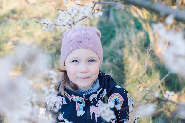 Foto retrato de una niña en el fondo de un árbol de flores de primavera