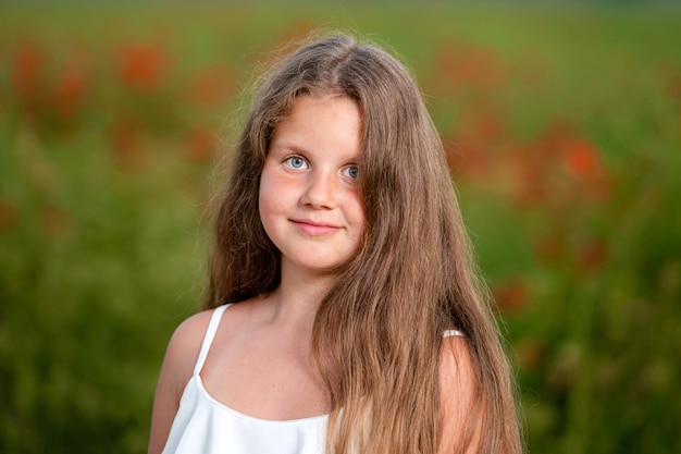 Retrato de una niña en el fondo de un campo de amapolas en el primer plano de la luz del sol de la tarde