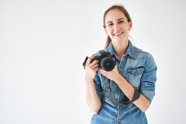 Retrato de una niña fotógrafa sobre un fondo blanco.