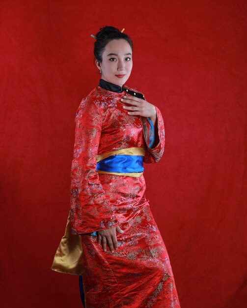 Retrato de una niña geisha sobre un fondo rojo.