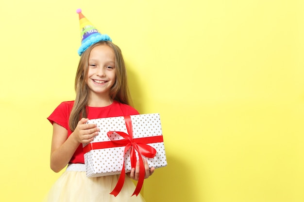 Retrato de una niña con un gorro festivo y con un regalo en sus manos