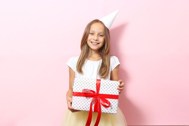 Retrato de una niña con un gorro festivo y con un regalo en sus manos