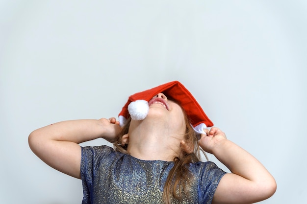 Retrato de una niña con un gorro de Papá Noel sobre un fondo gris, espacio de copia