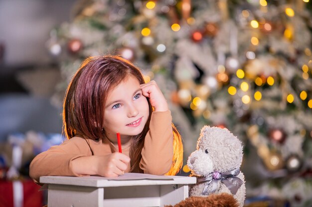 Retrato de una niña con una gran carta escribiendo a Santa Claus