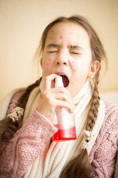 Retrato de niña con gripe con spray para la garganta