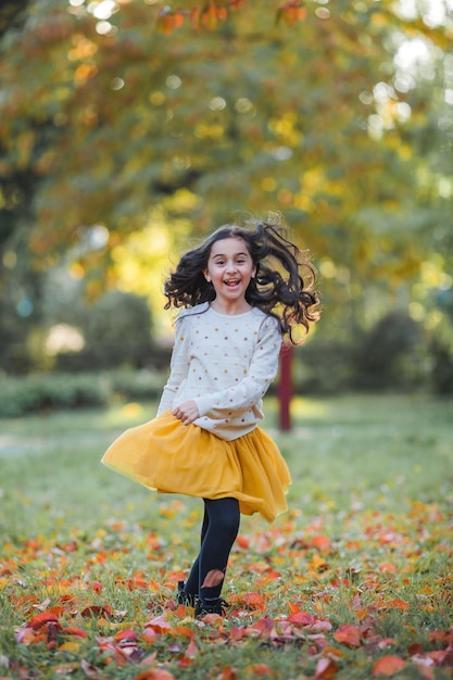 Retrato de una niña hermosa de 9 años con el pelo largo y oscuro en ropa brillante Niño feliz en el parque de otoño