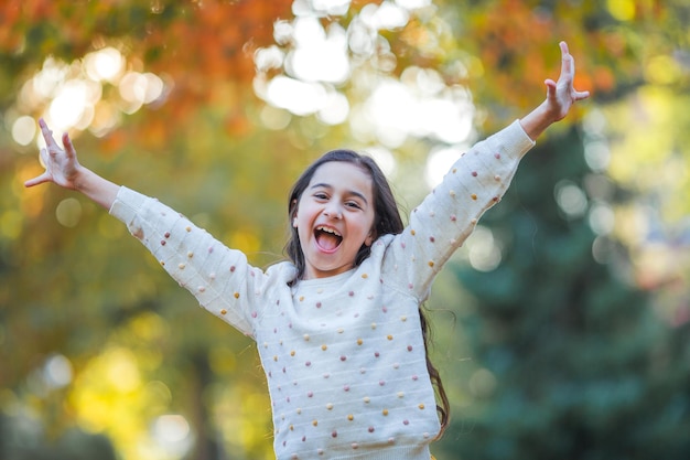 Retrato de una niña hermosa de 9 años con el pelo largo y oscuro en ropa brillante Niño feliz en el parque de otoño