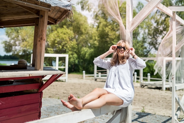 Foto retrato de niña hermosa en la glorieta de madera blanca en el lago, disfrutar y relajarse en la naturaleza