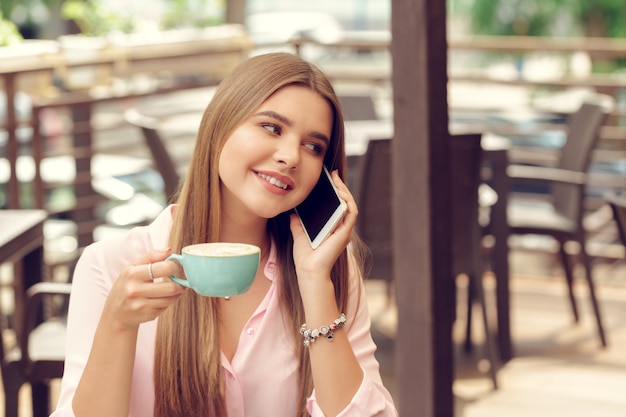 Retrato de niña hermosa con su teléfono móvil en la cafetería.