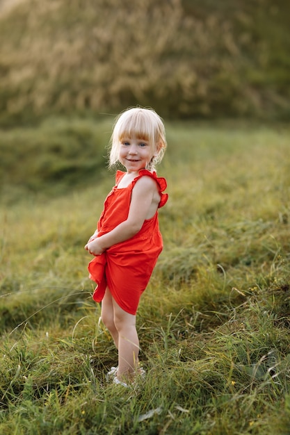 Retrato de una niña hermosa en vestido rojo en la naturaleza en las vacaciones de verano