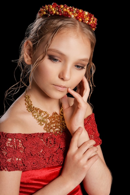 Retrato de niña hermosa en vestido rojo sobre fondo negro