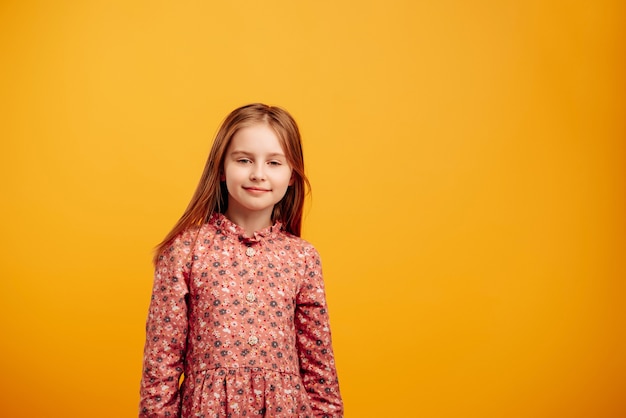 Retrato de niña con hermoso vestido aislado sobre fondo amarillo