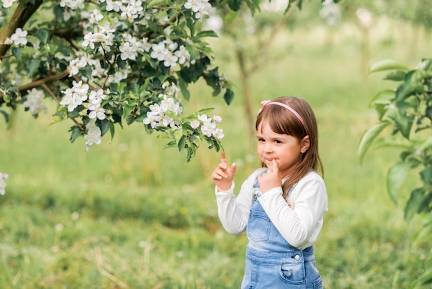 Retrato de una niña en un jardín de primavera cerca de manzanos en flor