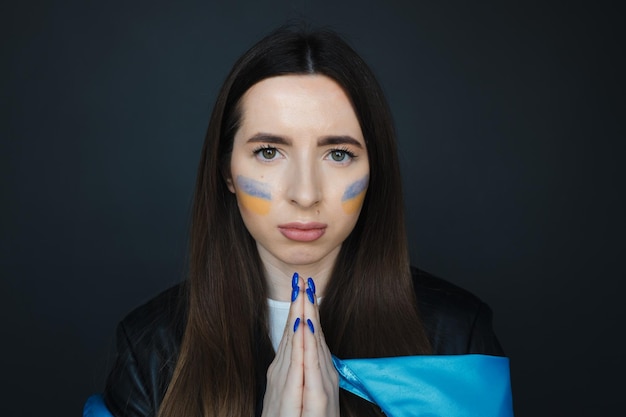 retrato, de, niña joven, con, azul y amarillo, bandera ucraniana, en, ella, mejilla, en, fondo negro