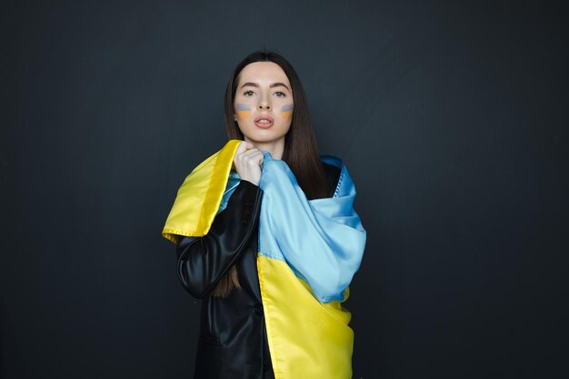 retrato, de, niña joven, con, azul y amarillo, bandera ucraniana, en, ella, mejilla, en, fondo negro