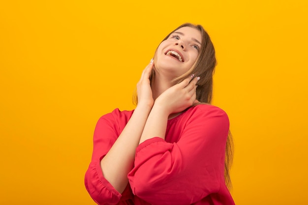 retrato, de, niña joven, feliz, reír, y, mirar hacia arriba, mujer joven, en, camisa roja, en, un, fondo amarillo