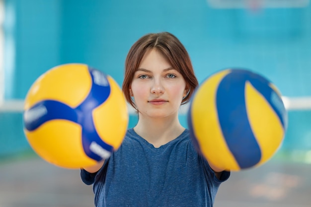 retrato, de, un, niña joven, tenencia, dos, pelotas de voleibol, viejo, y, nuevo, voleibol, en, manos, de, un, niña