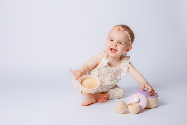 Retrato de una niña jugando con platos de juguetes de madera sobre un fondo blanco