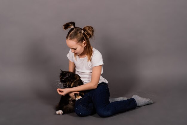 Retrato de una niña jugando con su mascota, gato grande negro