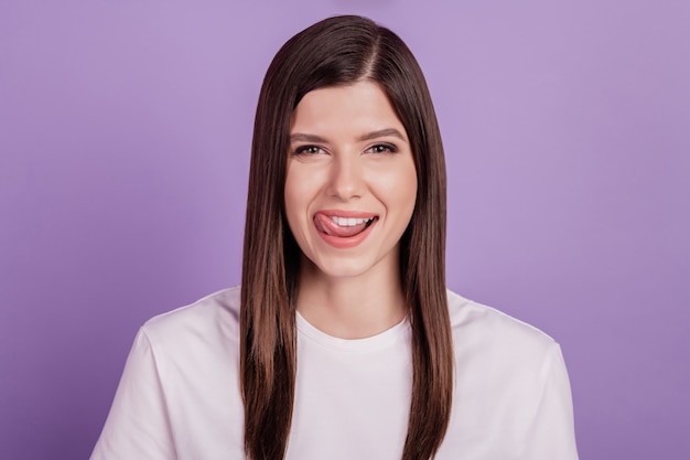 Retrato de niña lamiendo el labio dientes sanos blancos aislados sobre fondo púrpura