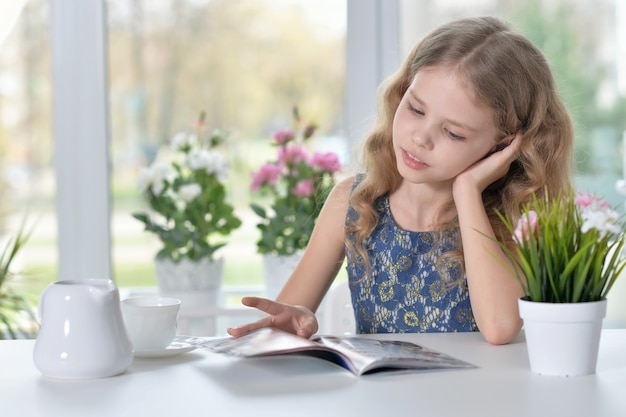 Retrato de una niña leyendo y bebiendo té