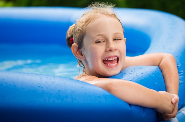 Retrato de niña linda en azul piscina inflable grande al aire libre