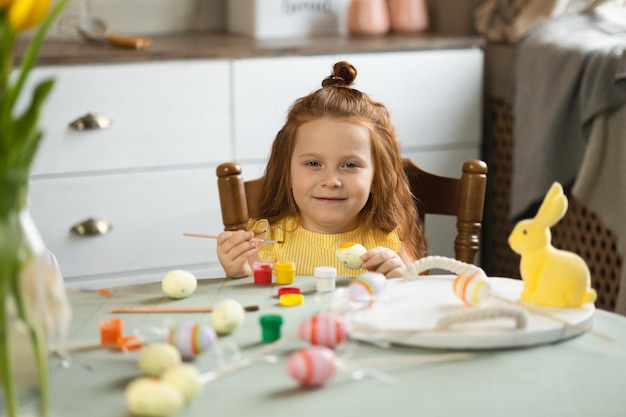 Retrato de niña linda con cepillo para colorear huevos de Pascua