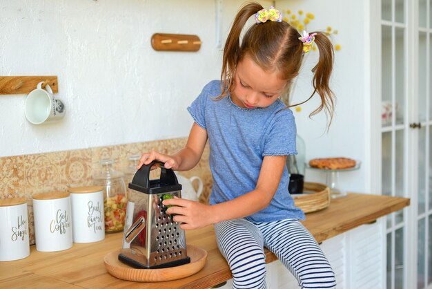 Retrato de una niña linda en la cocina con abarrotes y comida sana