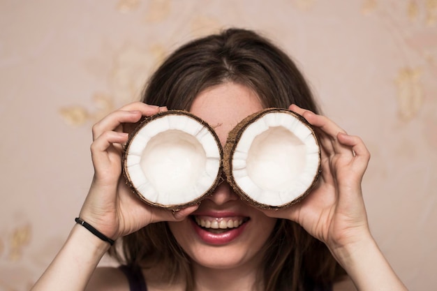 Retrato de niña linda con cocos cerca de sus ojos.