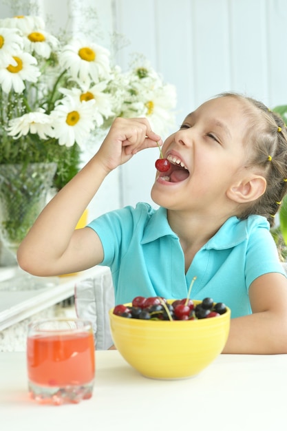 Retrato de niña linda comiendo cerezas