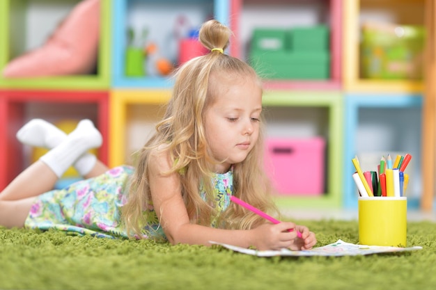 Retrato de niña linda dibujando en casa en el piso