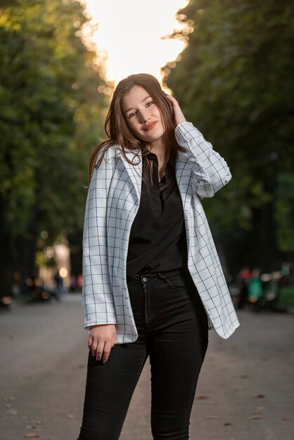 Retrato de niña linda estudiante en el fondo del parque Mujer atractiva joven en chaqueta a cuadros