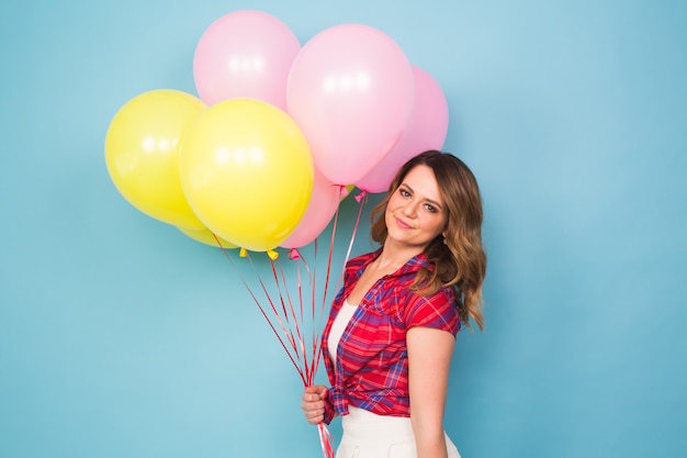 Retrato de niña linda en un estudio sonriendo y jugando con globos amarillos y rosados, fondo con copyspace. Concepto de fiesta, celebración y personas.