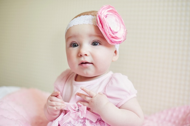 Retrato de niña linda con flor de lazo rosa en la cabeza.